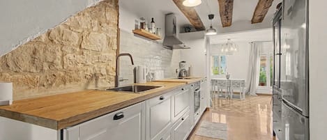 A kitchen with a stone wall, wooden countertop, and a large refrigerator.