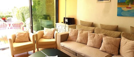 A living room with a sofa, armchairs, a coffee table, and a TV.