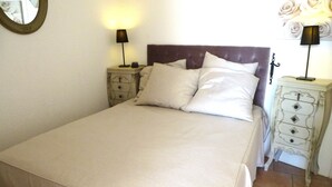 Una cama bien hecha con cabecera, dos mesitas de noche con lámparas y un aparador con cajones.