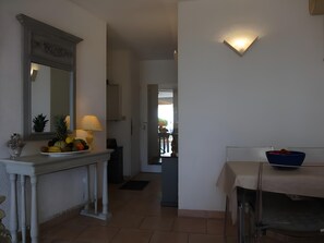 A hallway with a white wall, a mirror, a fruit bowl, a table with a blue bowl, and a door leading to another room. - Bright Apartment by the Ligurian sea (La Croix-Valmer)