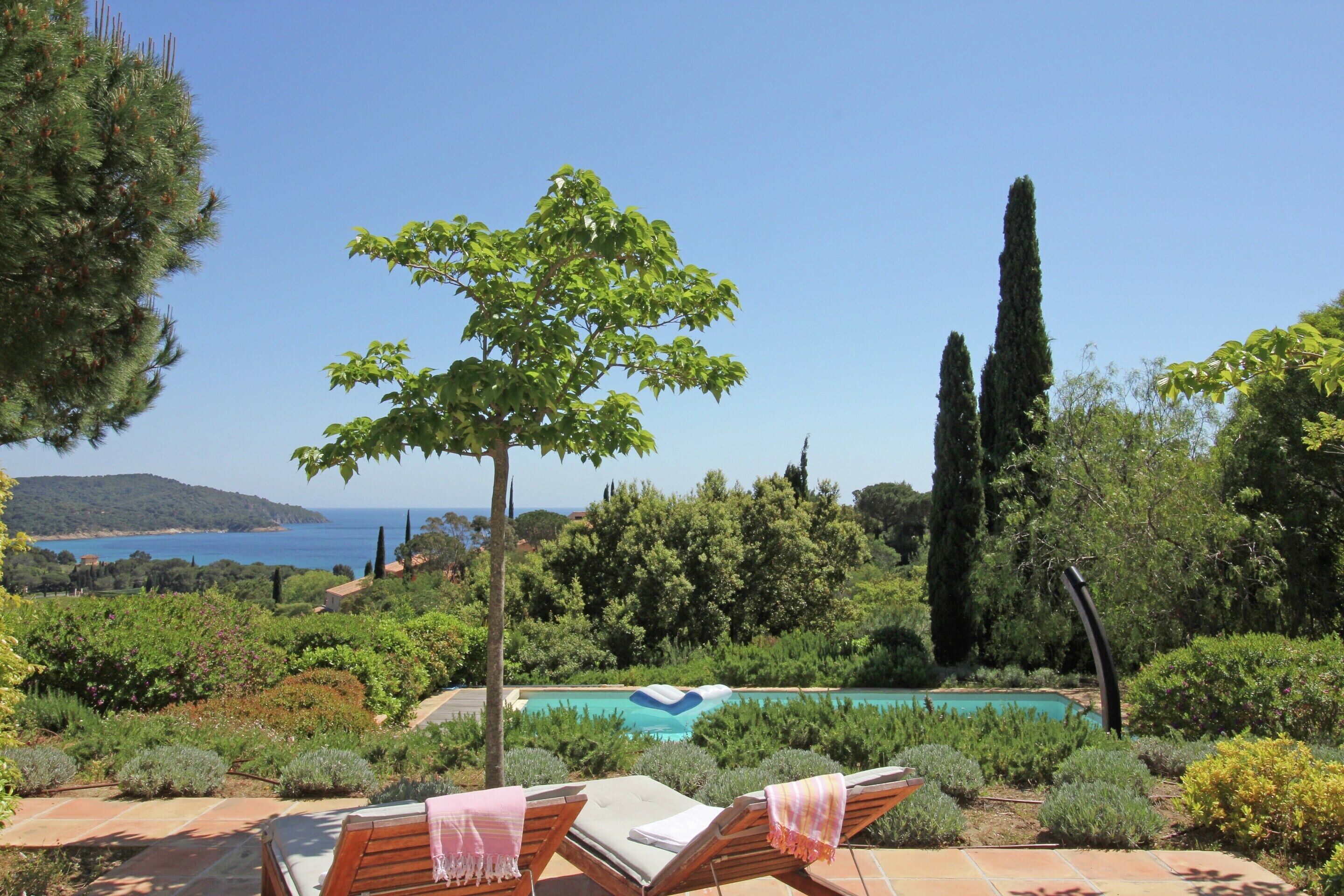 A poolside area with lounge chairs and a view of the sea.