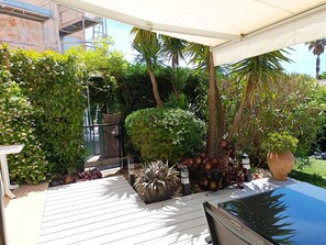A covered outdoor area with a wooden deck, potted plants, and a car parked nearby. - Bright Apartment by the Ligurian sea (La Croix-Valmer)