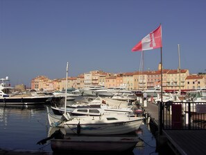 A marina with boats docked, a flag, and buildings in the background. - Bright Apartment by the Ligurian sea (La Croix-Valmer)