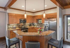 A kitchen with wooden cabinets, stainless steel appliances, a granite countertop, and pendant lighting. - Spacious 1-bedroom condo 10 min walk from the national park! (West Yellowstone)