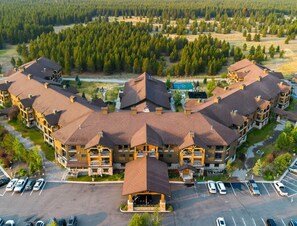 A multi-story hotel with a central courtyard, outdoor pool, and a parking lot. - Spacious 1-bedroom condo 10 min walk from the national park! (West Yellowstone)