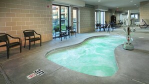 Zona de piscina con equipo de ejercicios, sillas y un cartel que indica 'no saltos, profundidad de 0,9 metros'.
