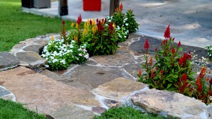A stone pathway bordered by grass and flower beds with red and white flowers. - The Winchester Cabin —Rustic Warmth Meets Modern Comfort (Harriet)