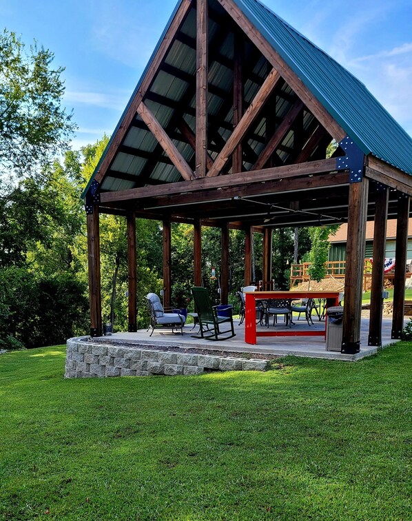 A covered outdoor seating area with stone steps, wooden beams, and a metal roof.