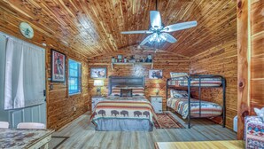A cabin interior with a bed, bunk beds, a ceiling fan, and wooden walls. - The Winchester Cabin —Rustic Warmth Meets Modern Comfort (Harriet)