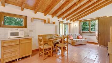 A cozy kitchen with wooden cabinets, a dining table, and a built-in microwave.