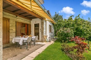 A stone building with a covered outdoor seating area and a garden. - Chalet La Gigliola (Laveno Mombello)