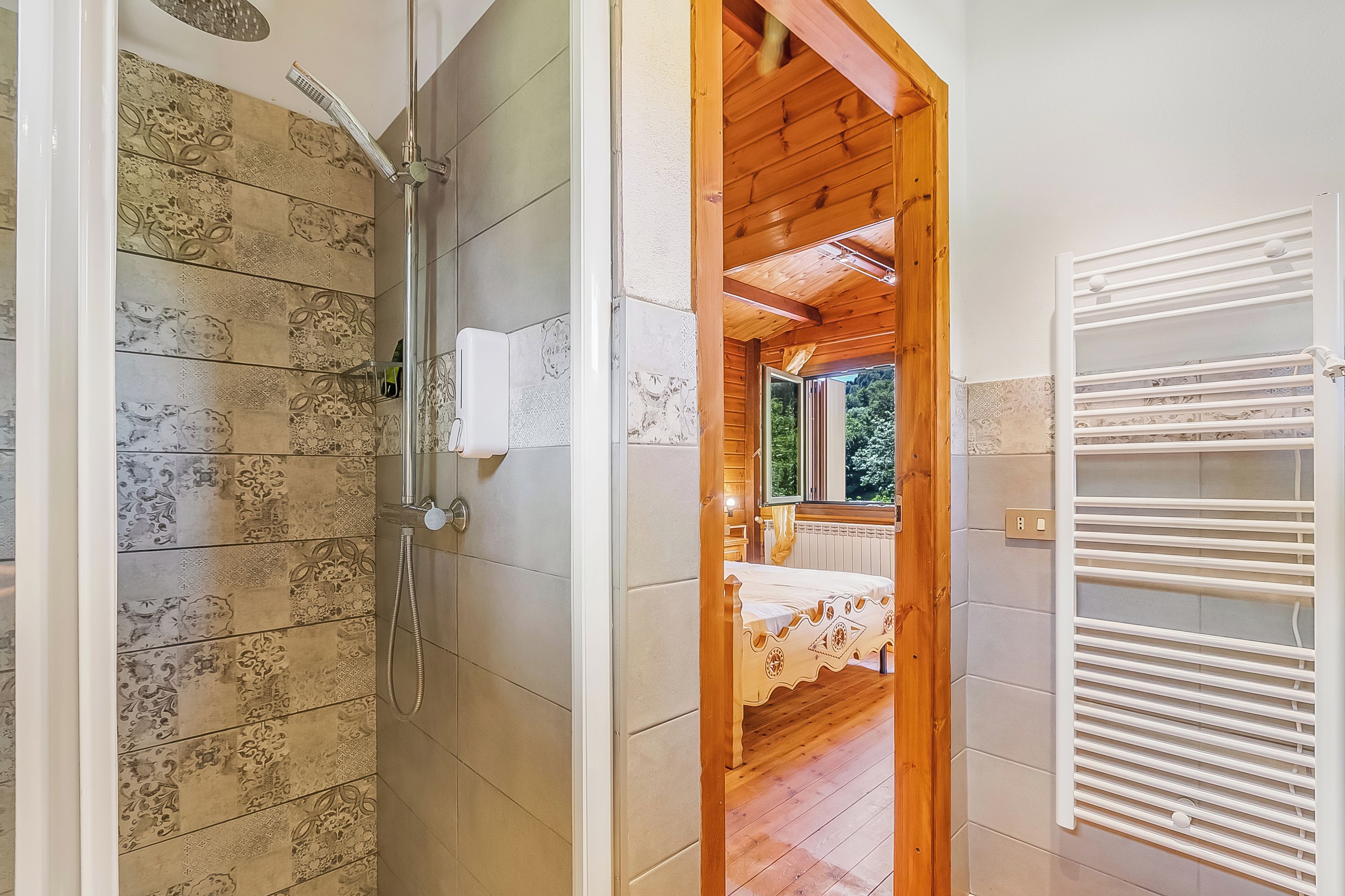 A bathroom with patterned tiles, a shower, and a visible toilet paper holder.