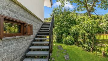 A staircase leading to a building with a stone facade and a window with wooden shutters.