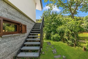 A staircase leading to a building with a stone facade and a window with wooden shutters.