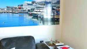 Un soggiorno con un divano, un tavolino con una rivista e un'ampia finestra vista sul porto.