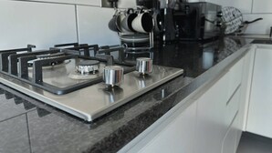 Una cucina moderna con piano cottura a gas, elettrodomestici in acciaio inossidabile e mobili bianchi.