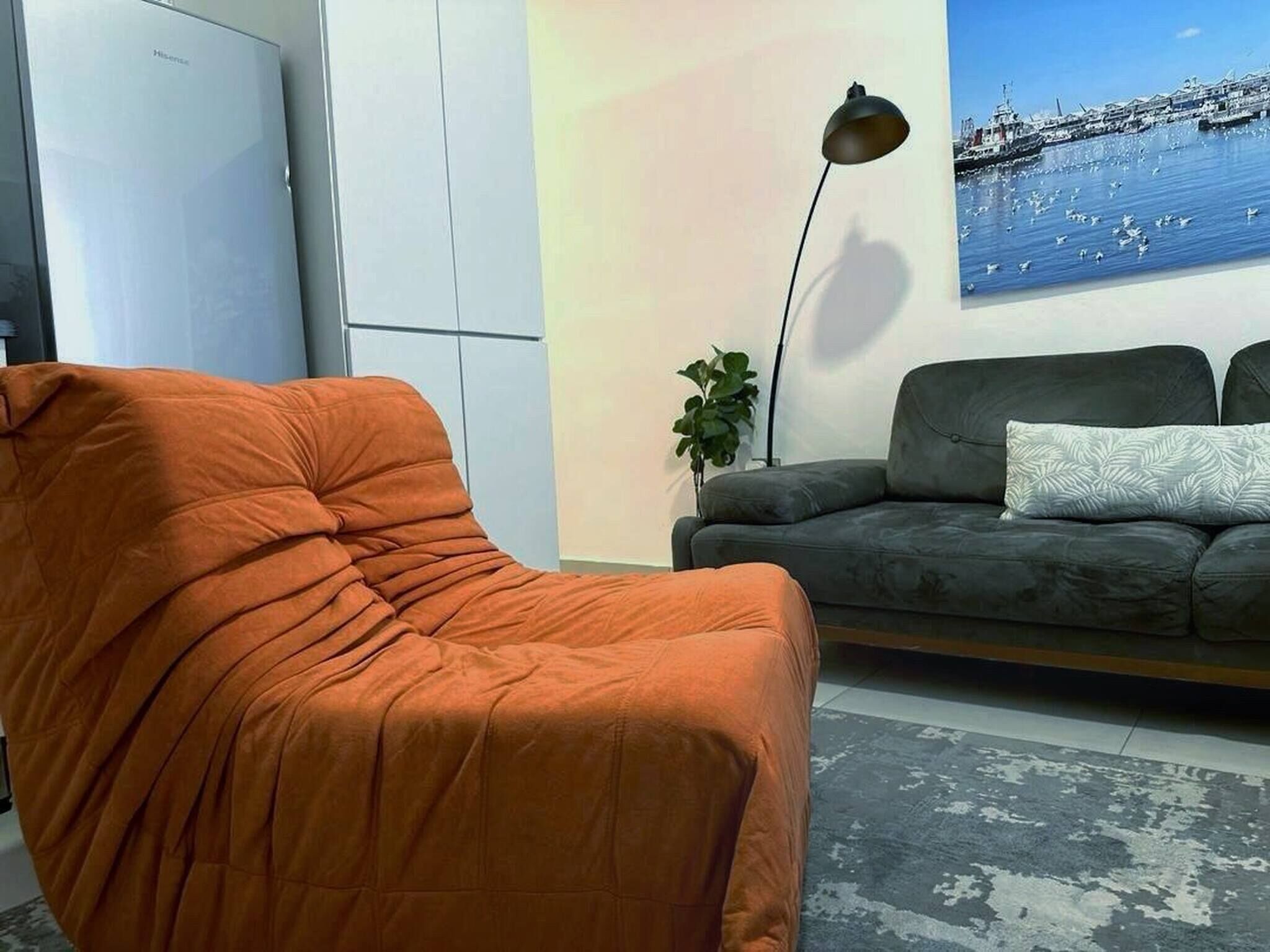 Un salon comprenant un canapé, un fauteuil, une lampe sur pied et un tableau mural.
