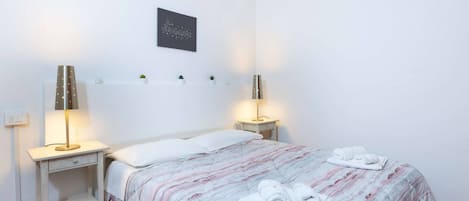 Una cama bien hecha con una colcha a rayas y dos toallas enrolladas al lado.