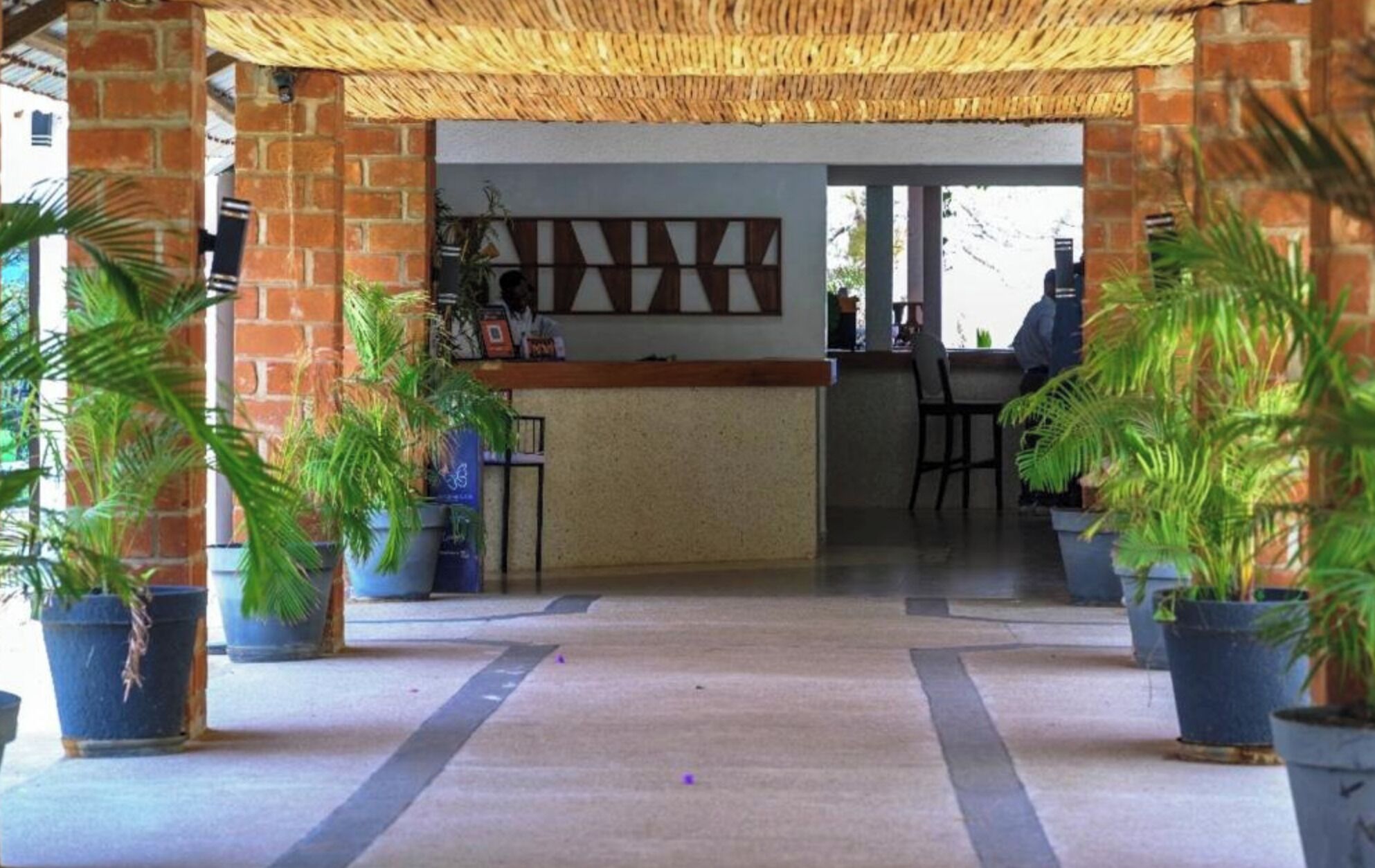 Uma área de recepção com parede de tijolos, balcão e plantas em vasos.