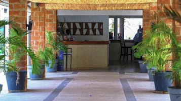 Uma área de recepção com parede de tijolos, balcão e plantas em vasos.