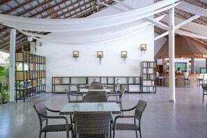 Un espace intérieur spacieux avec des tables et des chaises, un coin salon avec un banc et un comptoir avec un téléviseur.
