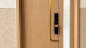 Una puerta de madera con un picaporte vertical y un ventanal pequeño.