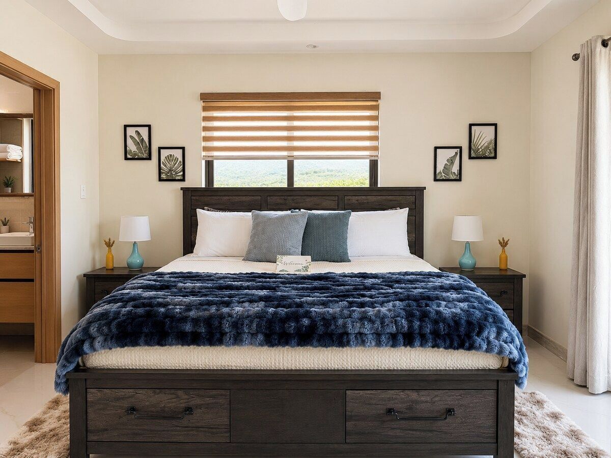 Ein Schlafzimmer mit einem dunklen Holzbett, weißer Bettwäsche, einer flauschigen blauen Decke und einem Fenster mit Jalousien.