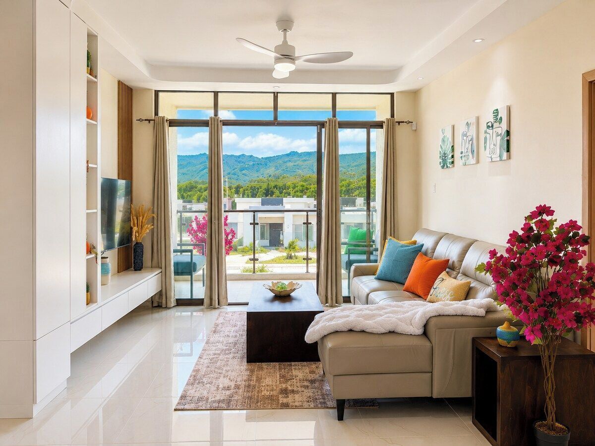 A modern living room with a sofa, coffee table, and a view of a mountainous landscape through large windows.