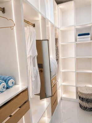 A modern bathroom with a vanity, a mirror, and a built-in shelf with towels.