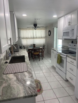 A kitchen with a marble countertop, a dining table with chairs, and a microwave. - Charming 2-bedroom house with pool in Englewood (Englewood)