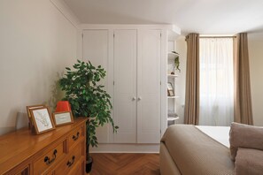Een slaapkamer met een bed, een dressoir, een plant en een kast.