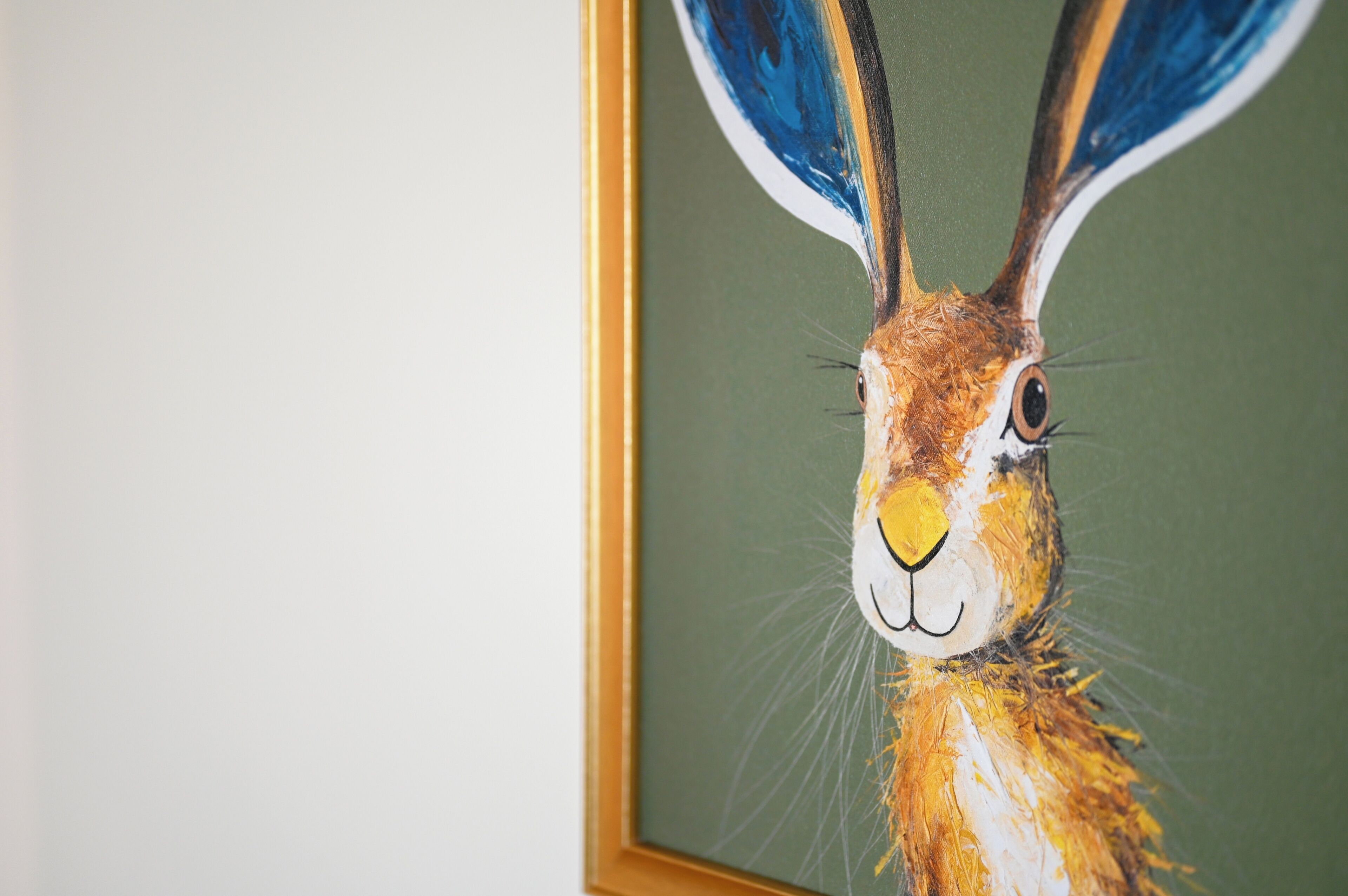 A framed painting of a rabbit with large ears and a prominent nose.