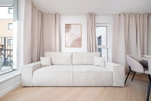 A modern living room with a striped sofa, a framed abstract artwork, and a view of the outside. - Łódź City Center Apt — Parking & Terrace (Łódź)
