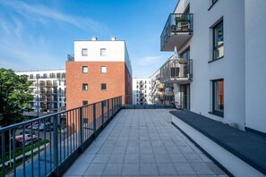 Kattohuoneistossa on terassi, jossa on metallikaide, ja sieltä on näkymä viereisiin rakennuksiin sekä avoin näkymä taivaalle.
