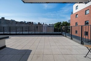 A rooftop terrace with a tiled floor, a metal railing, and a view of the cityscape. - Łódź City Center Apt — Parking & Terrace (Łódź)