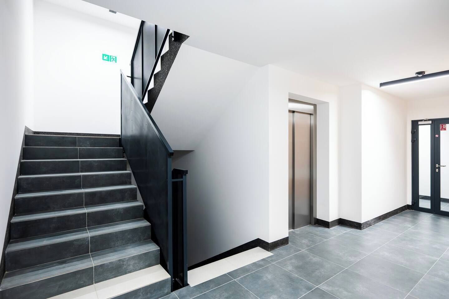 A modern interior with a staircase, a door, and a wall-mounted sign.