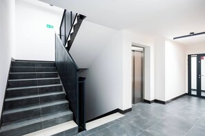 A modern interior with a staircase, a door, and a wall-mounted sign. - Łódź City Center Apt — Parking & Terrace (Łódź)