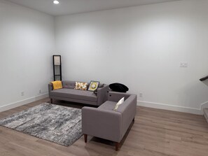 A modern living room with a grey sofa, a matching armchair, and a grey shaggy rug. - Lovely 3-bedroom with AC in Fort Worth, centrally located (Fort Worth)