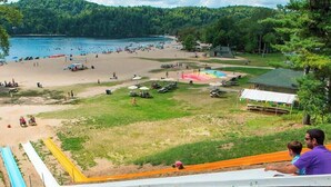 Une plage avec un toboggan aquatique, une zone sablonneuse et un terrain herbeux où sont installées des tentes.