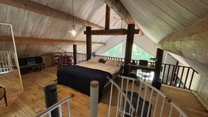 Une pièce aux hauts plafonds, comprenant un lit, un bureau et offrant une vue sur l’extérieur.