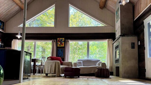 Une pièce spacieuse avec un plafond haut, de grandes fenêtres, une cheminée et un coin salon confortable.