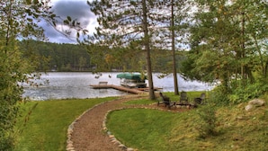 A lakeside property with a dock, a boat, and outdoor seating.