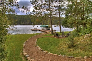 A lakeside property with a dock, a boat, and outdoor seating.