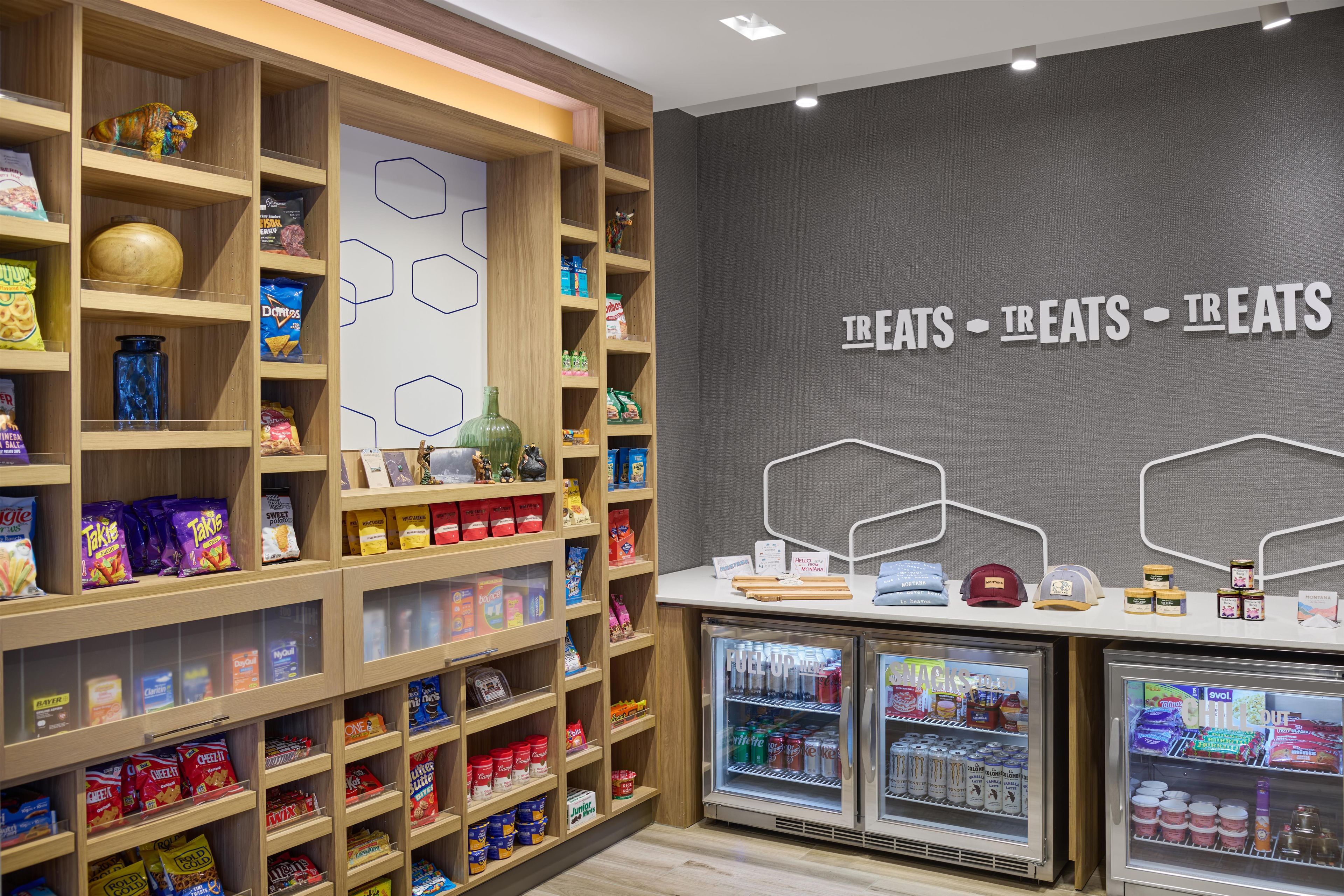Un kiosque proposant des collations et des boissons, avec un assortiment de produits emballés, notamment des chips, des biscuits et des boissons en bouteille.