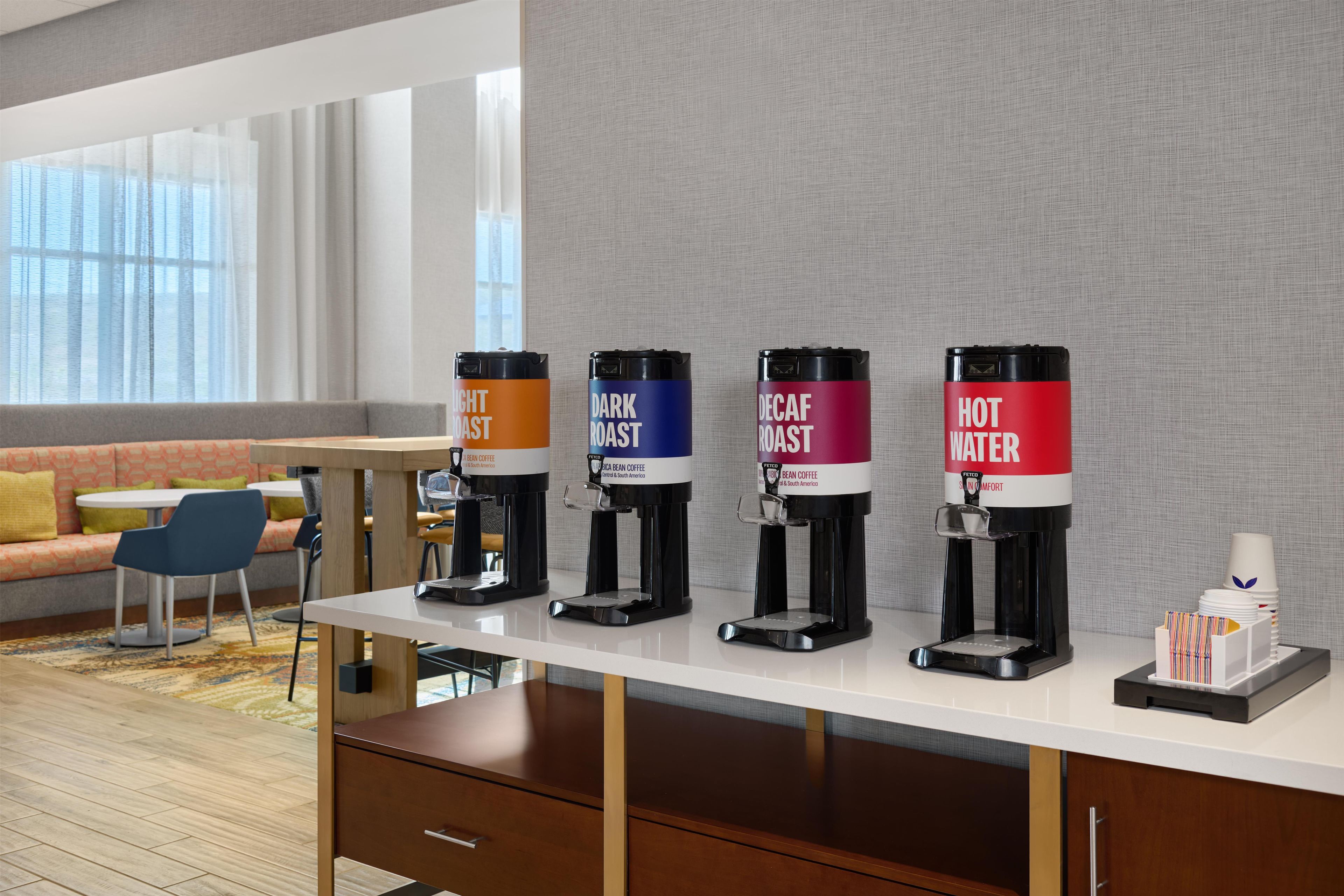 Een koffiehoek met vier koffiesoorten: een lichte branding, een donkere branding, decaf en heet water.