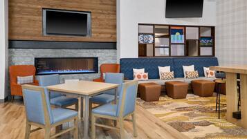 A modern lounge area with a fireplace, seating, and a flat-screen TV.