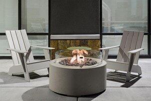 Un hogar con dos sillas Adirondack, una chimenea de piedra y vistas a través de amplios ventanales.