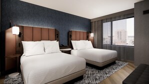 Habitación de hotel con dos camas, vistas a la ciudad y un diseño moderno.