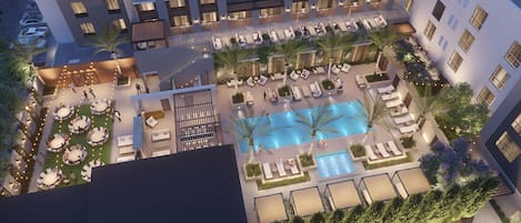 A hotel courtyard with a swimming pool, outdoor seating, and a covered area.