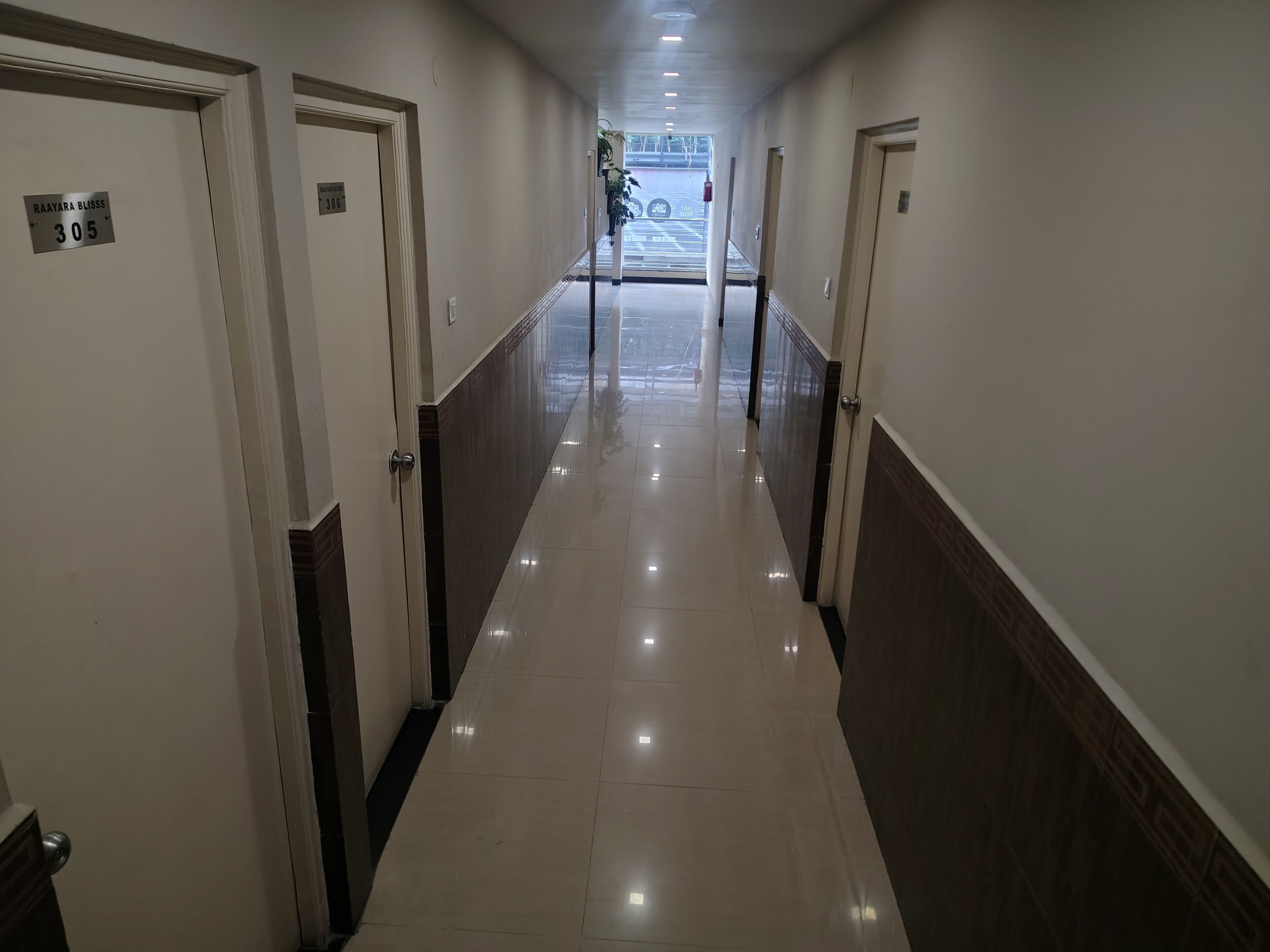 Pasillo de hotel con puertas numeradas 305 y 306, que da a un estacionamiento.